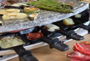 raclette grill with food on top and cheese melting in pans